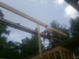Carpenter setting a ridge beam over a new addition frame — Ice Dam Removal by Roofing Brothers in Elliston