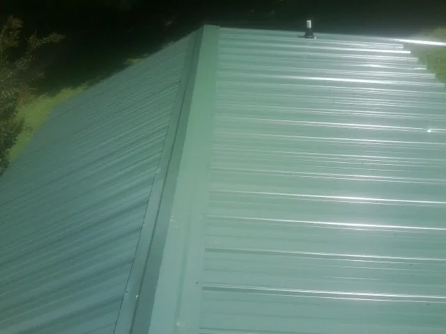 New green metal panels meeting at the ridge of a roof — Flat Roof Repair work by our crew in Elliston
